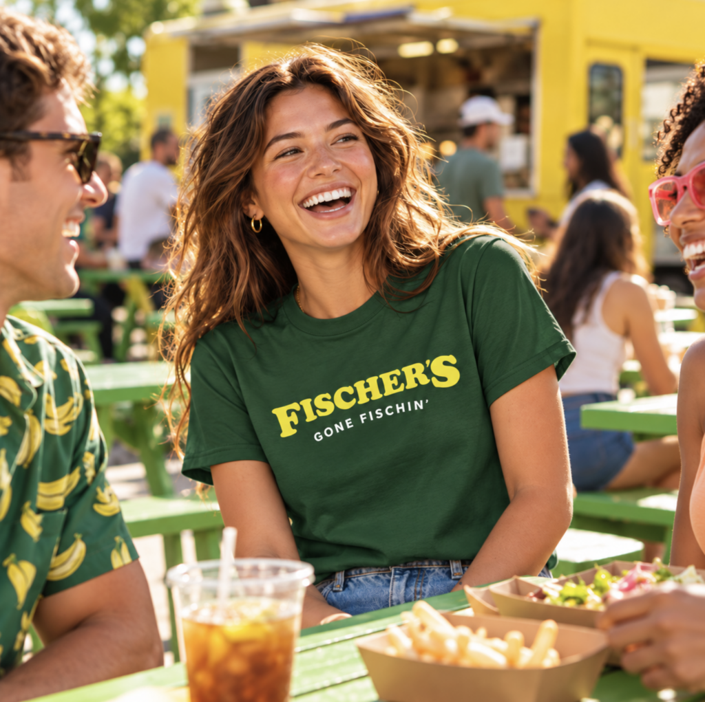 Woman wearing a green Fischer's shirt laughing with friends over food